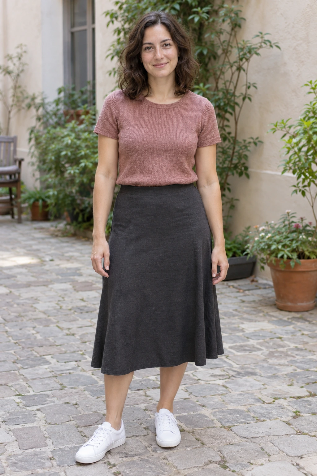 Fictional adult woman in a pink knit top, dark skirt and white sneakers, used for the generated birthday example