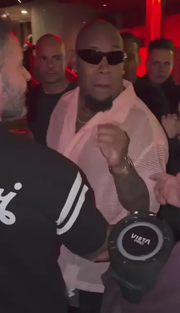Performer in sunglasses with a portable speaker in a crowded venue