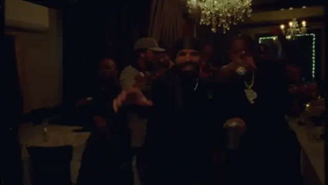 Performer surrounded by a crowd in a warmly lit house party